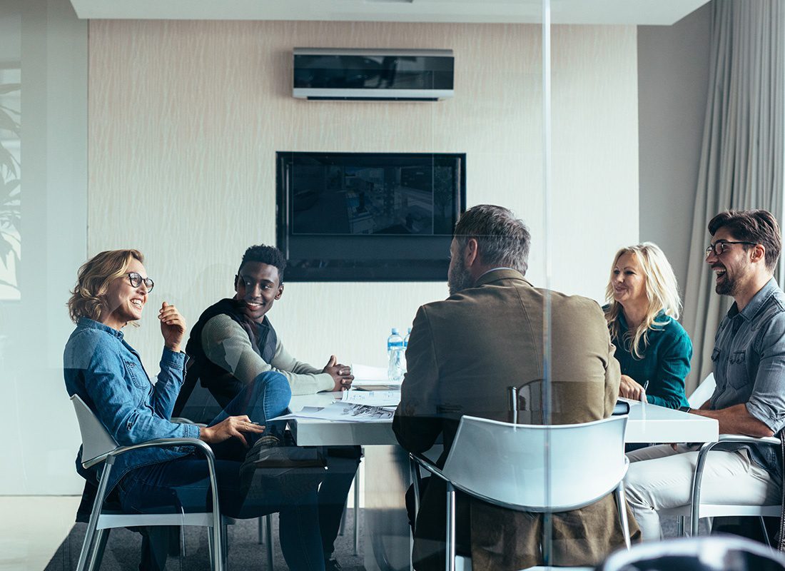 Insurance Solutions - Group of Professionals Sit Together to Have a Meeting Behind Glass Doors